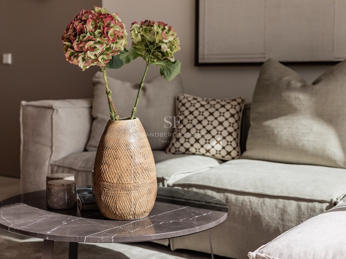 Nahaufnahme eines Couchtischs aus Marmor mit einer Vase Hortensien vor einem beigen Leinensofa.