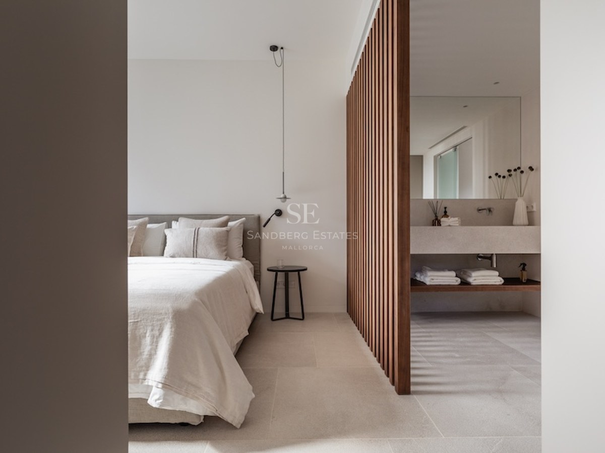 Modernes Hauptschlafzimmer mit Holzlamellen-Trennwand und integriertem En-Suite-Badezimmer mit Steinwaschtisch.