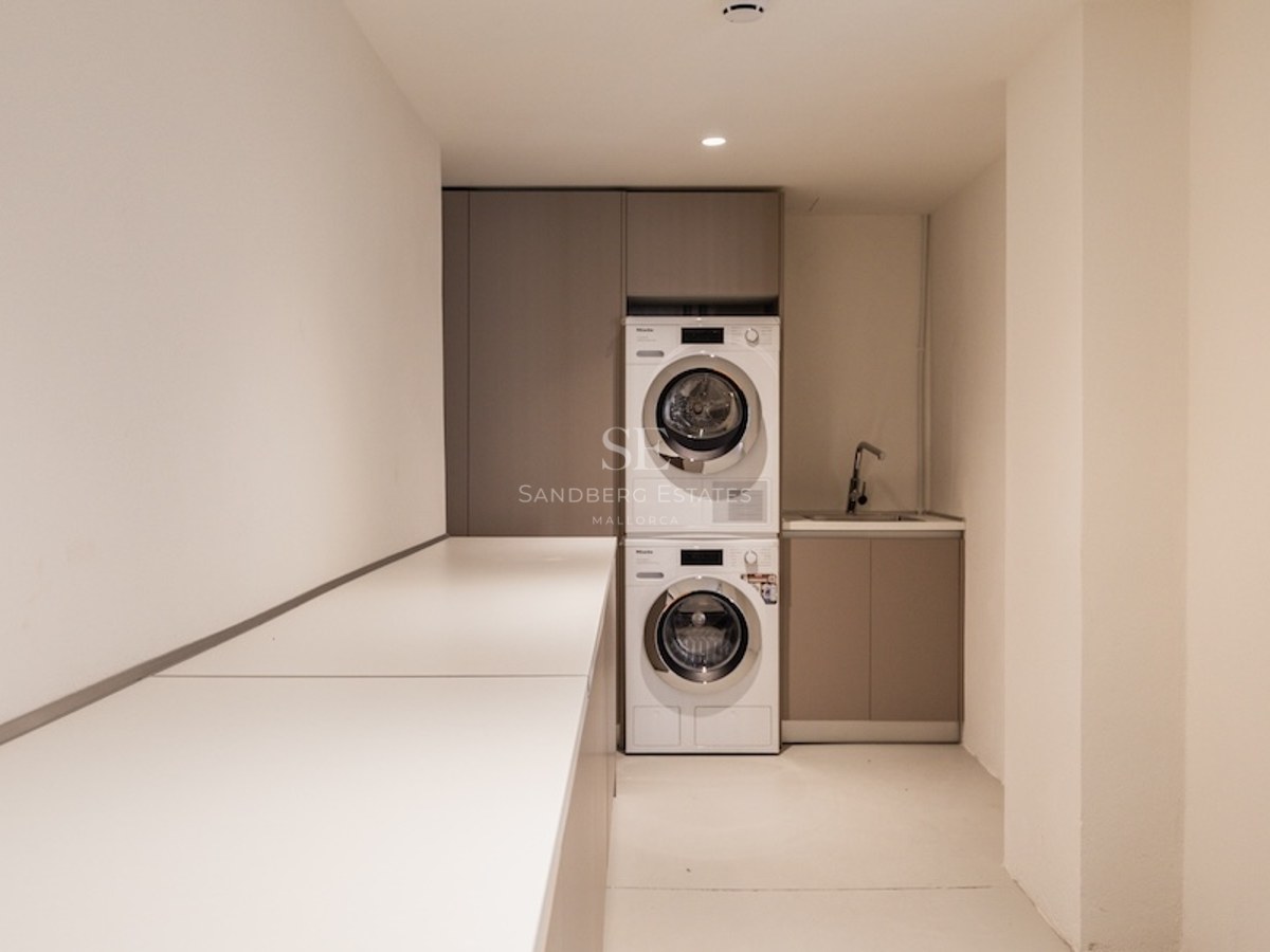 Gestapelte Miele Waschmaschine und Trockner in einem minimalistischen Hauswirtschaftsraum mit beigen Schränken.