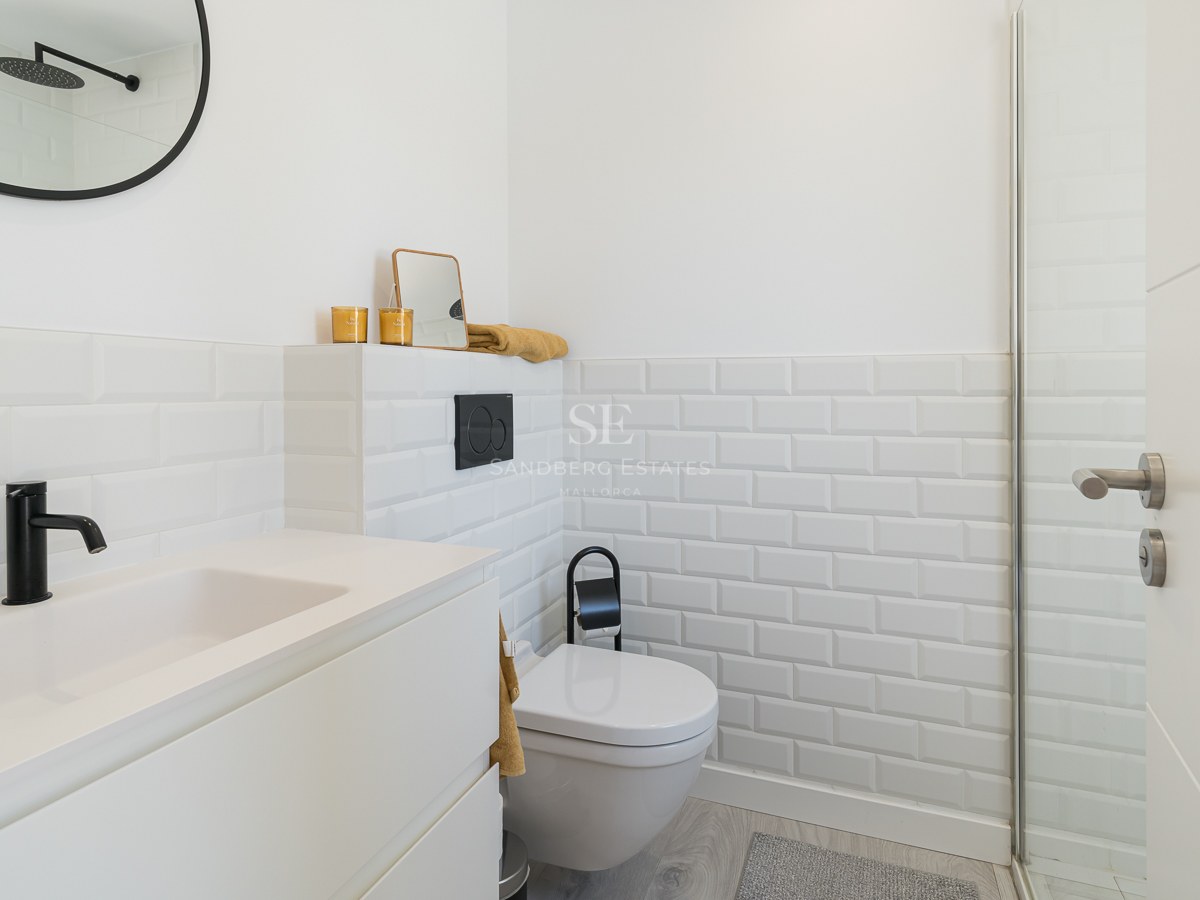 Modern white bathroom featuring subway tiles, black fixtures, and a sleek minimalist vanity.