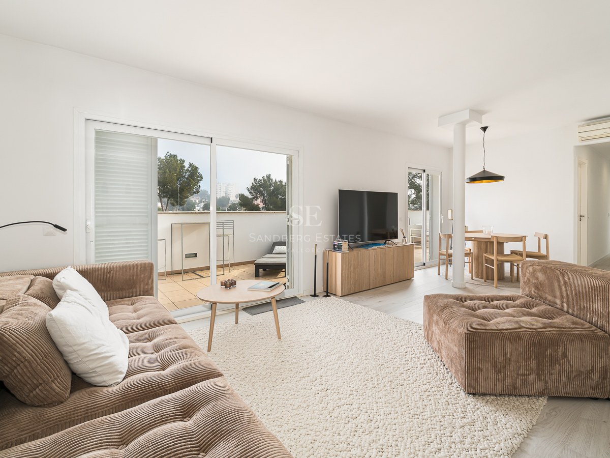 Modern living room with a brown corduroy sofa, large rug, and sliding glass doors leading to a sunlit terrace.