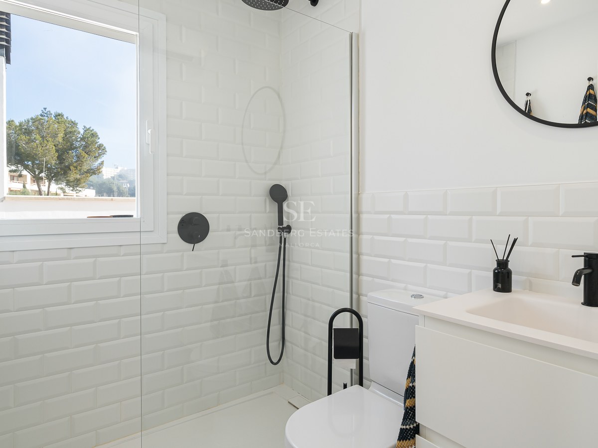 Bright bathroom featuring white subway tiles, a glass shower partition, and modern matte black fixtures.
