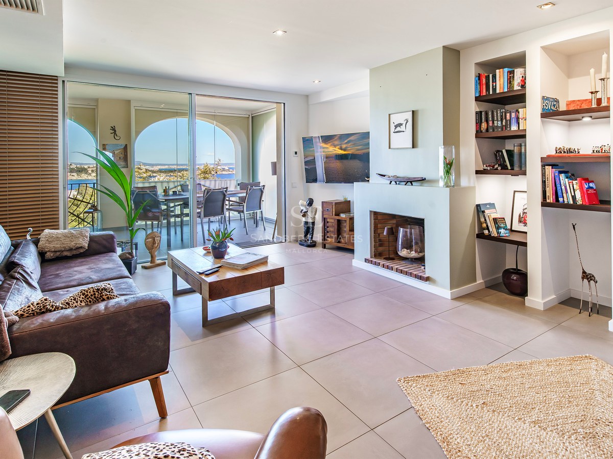 Bright living room featuring a leather sofa, integrated fireplace, and floor-to-ceiling sliding glass doors opening to a terrace.