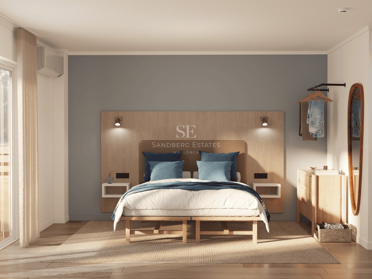 A bright master bedroom with a large bed, wooden headboard, blue pillows, and sunlight through a window.
