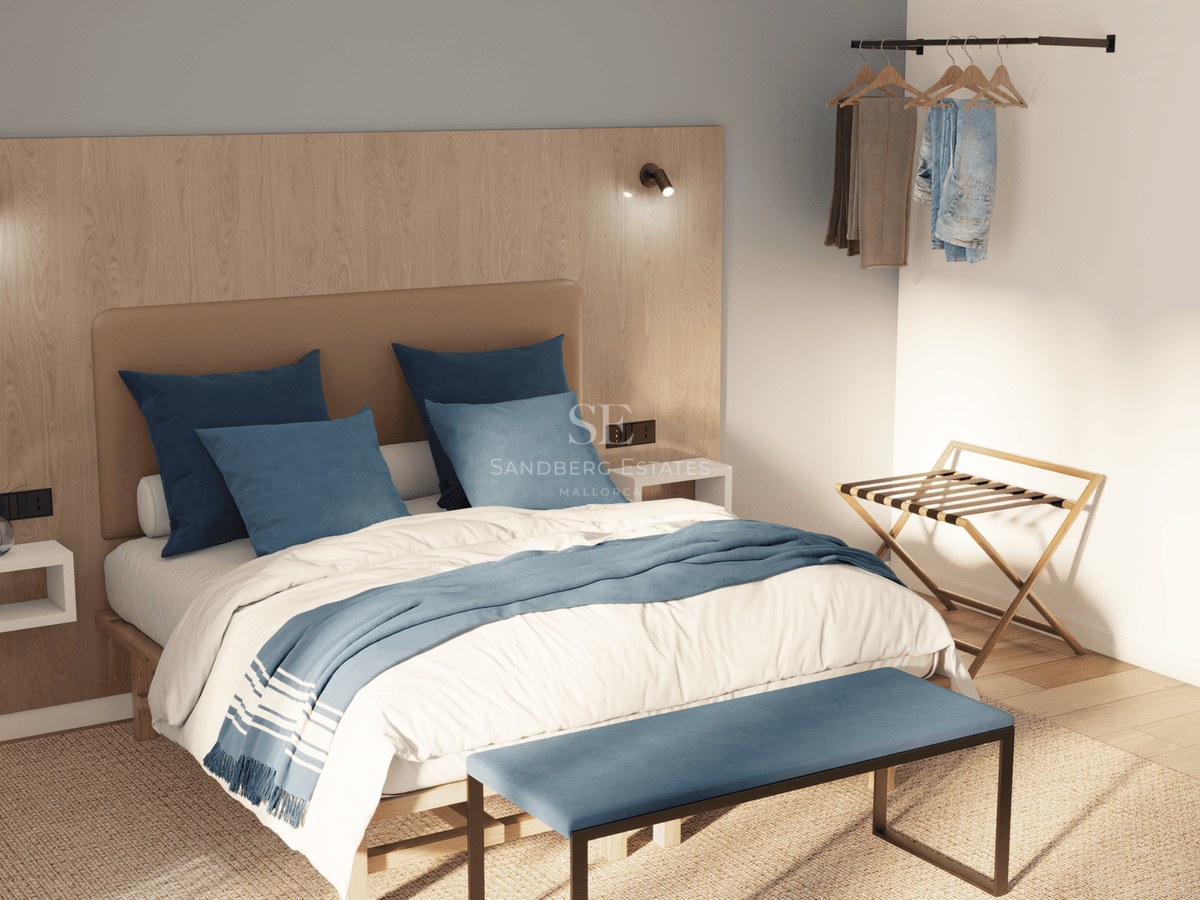 A modern bedroom featuring a wood-paneled headboard, blue pillows, a blue bench, and an oval mirror in bright daylight.