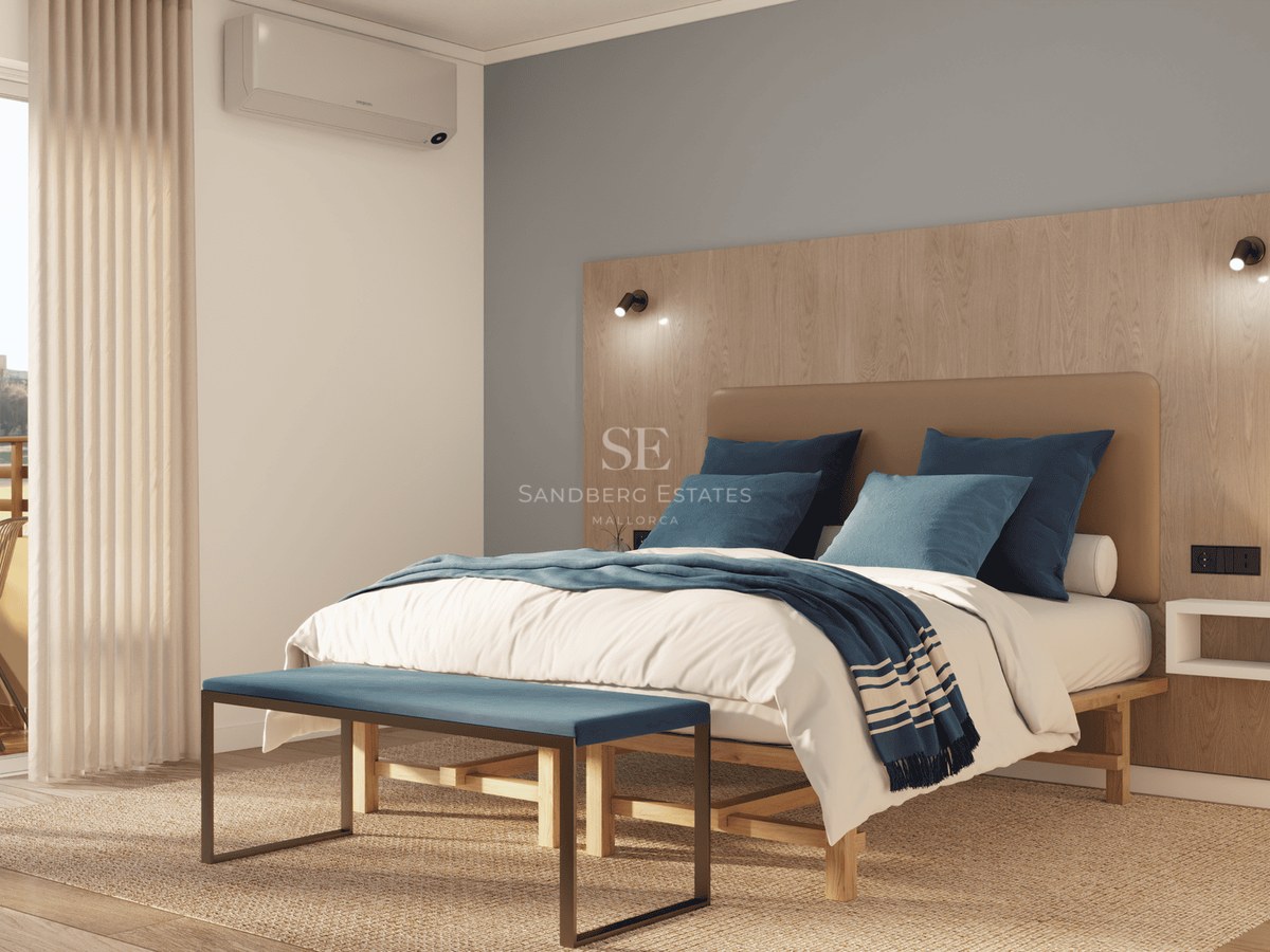 Bright bedroom featuring a double bed, wooden headboard, and access to a sunny balcony.