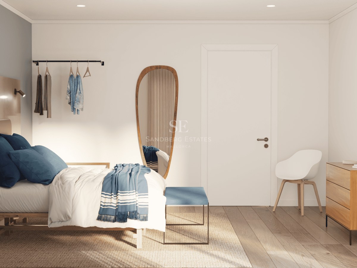 Bright bedroom featuring a bed with blue pillows, a tall organic mirror, and light oak wood furniture.