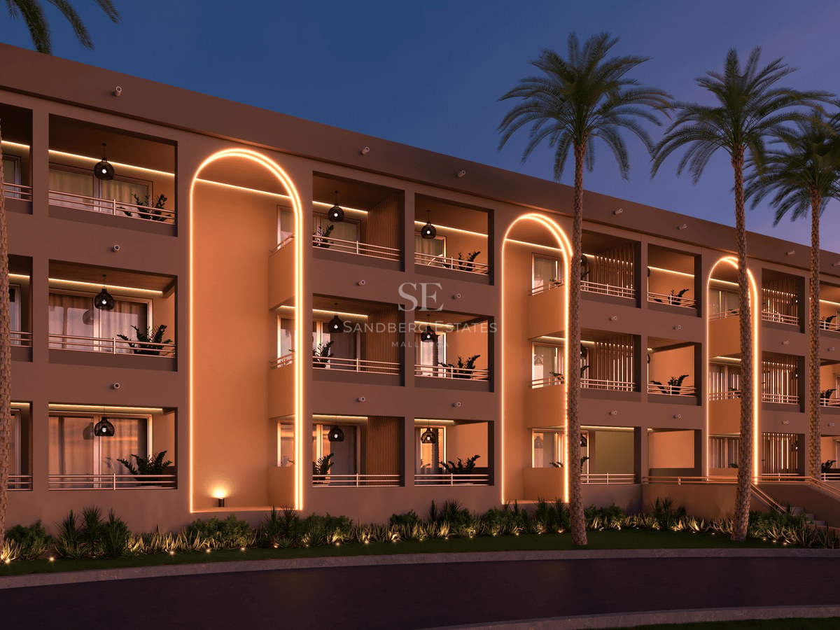 Modern building featuring illuminated golden arches, private balconies, and tall palm trees under a dusk sky.