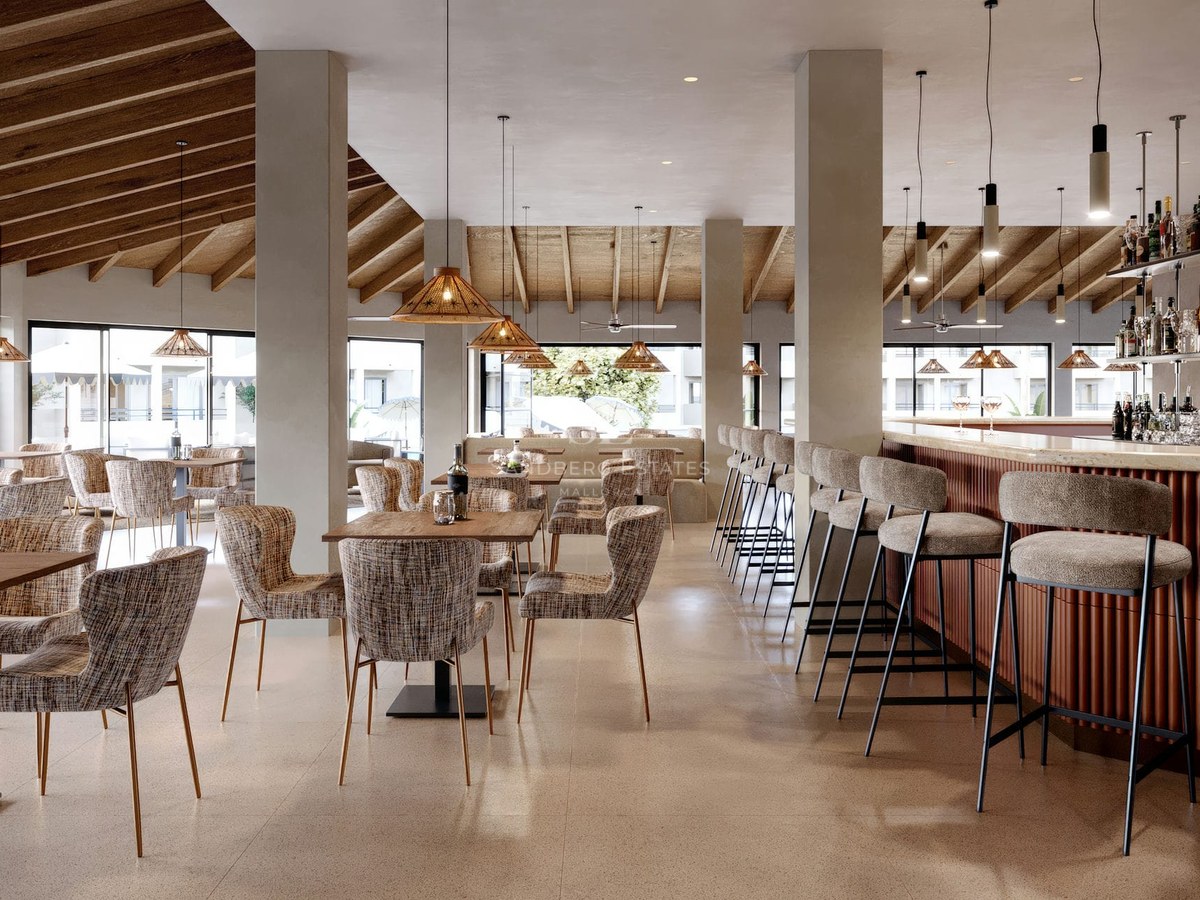Interior of a modern lounge featuring wooden ceilings, pendant lights, dining tables, and a bar with high stools.