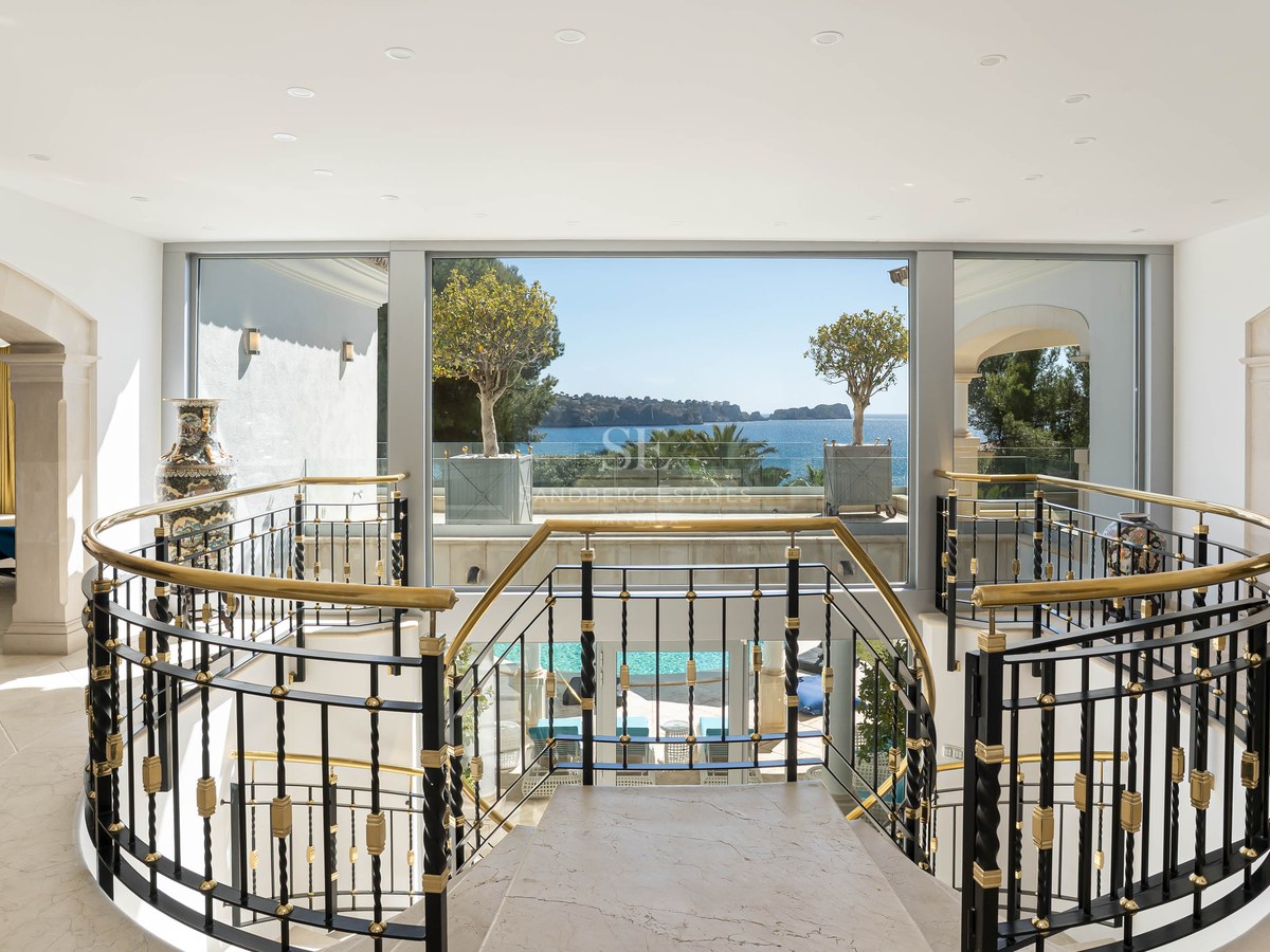 Vue intérieure d'un palier en marbre avec garde-corps orné donnant sur de grandes fenêtres et la mer Méditerranée.