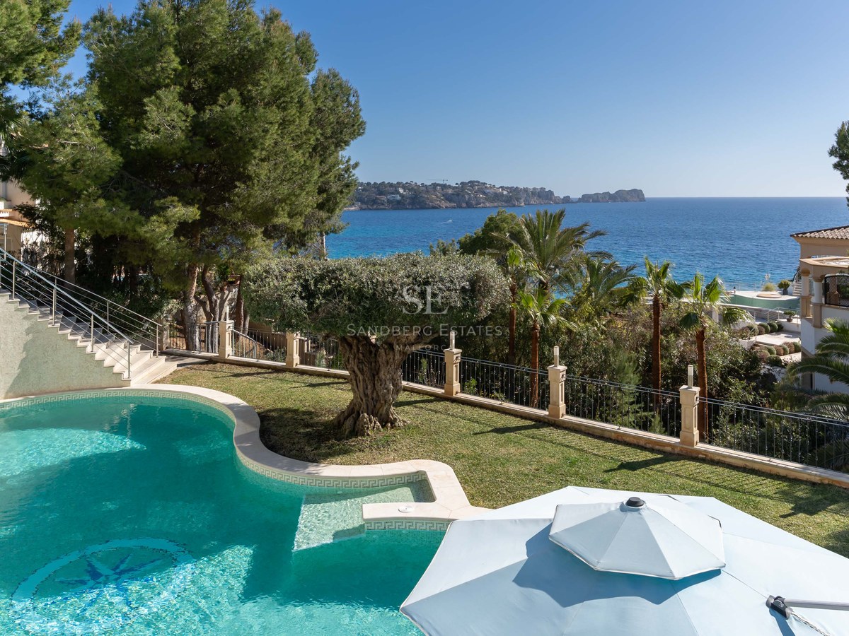 Piscine incurvée turquoise entourée de pelouse et d'oliviers surplombant la mer Méditerranée bleue.