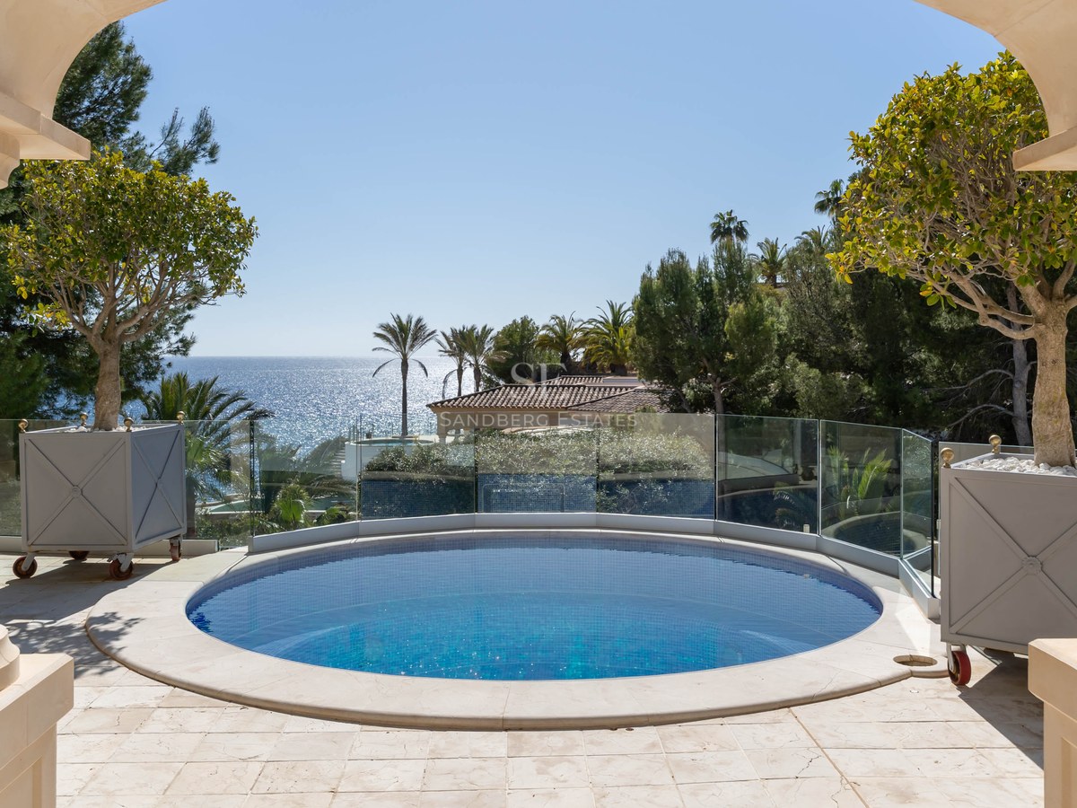 Piscine circulaire sur une terrasse en pierre avec garde-corps en verre donnant sur la mer Méditerranée.