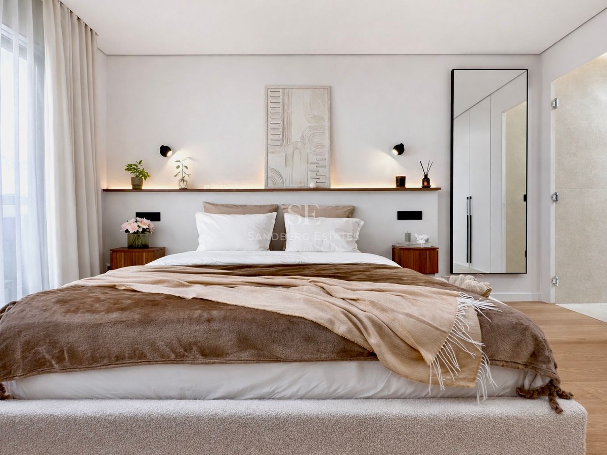 Bright master bedroom with a large bed, brown bedding, wooden nightstands, and integrated shelf lighting.
