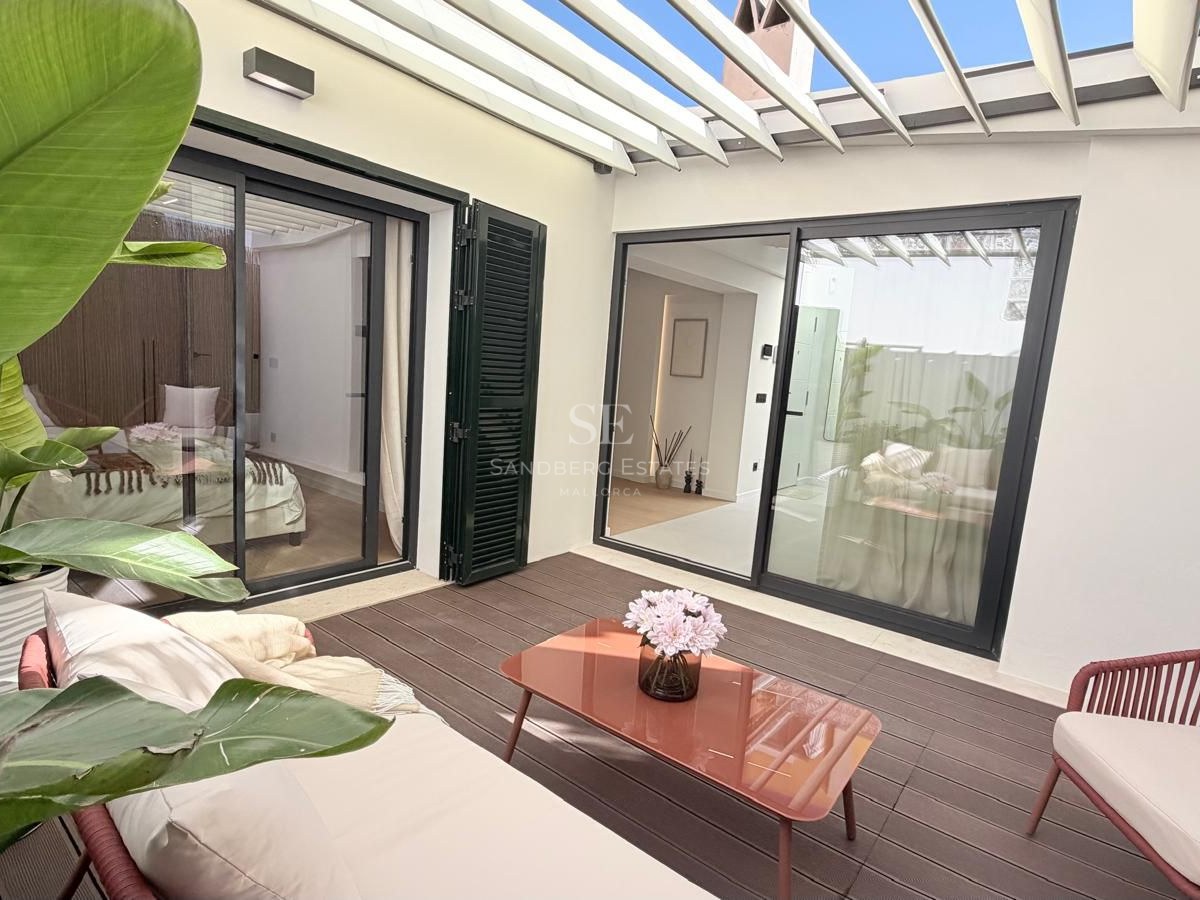 Outdoor patio with white pergola, wooden deck, terracotta-colored furniture, and tropical plants.