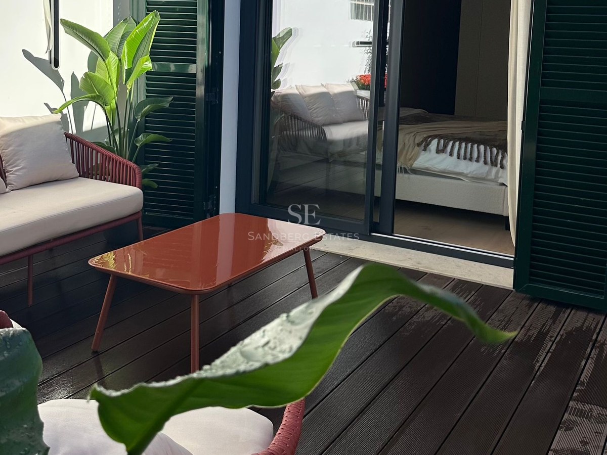 Private outdoor terrace with terracotta furniture, wooden decking, and green shutters next to a bedroom entrance.