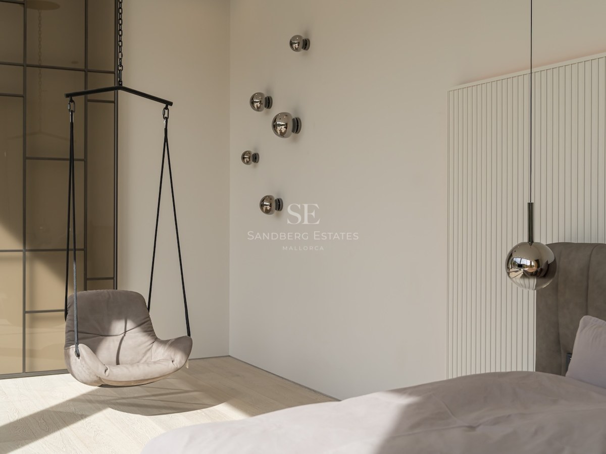 Coin de chambre moderne avec fauteuil suspendu gris, appliques murales sphériques et boiseries cannelées blanches.