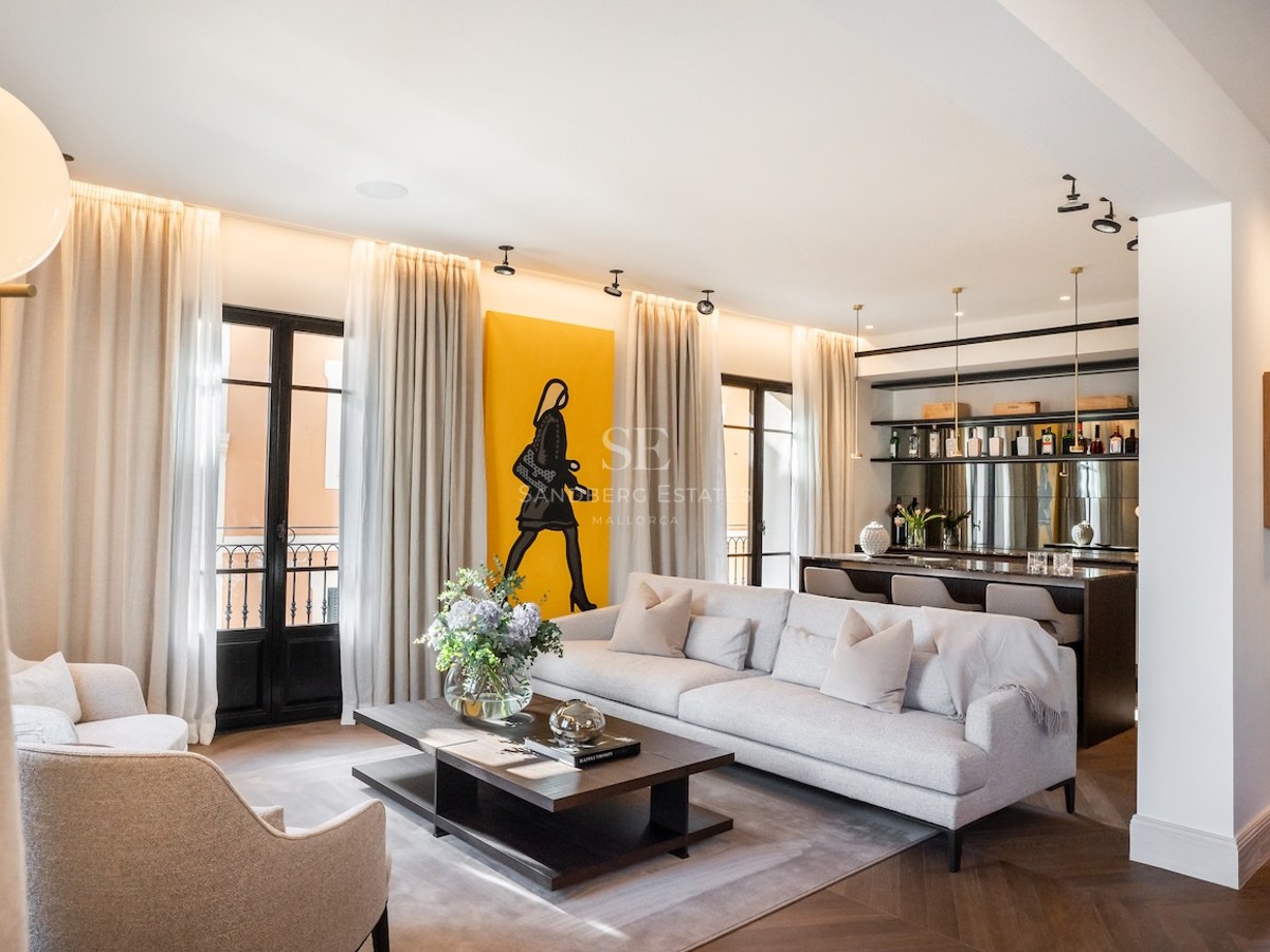 Sala de estar moderna con sofá gris, suelo de espiga, un gran cuadro amarillo y una zona de bar.