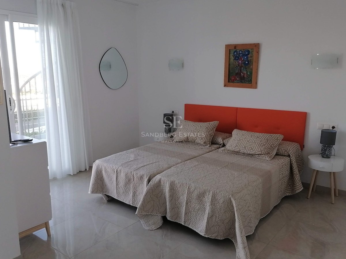 Bedroom featuring twin beds with an orange headboard, polished stone floors, and a glass door leading to a terrace.