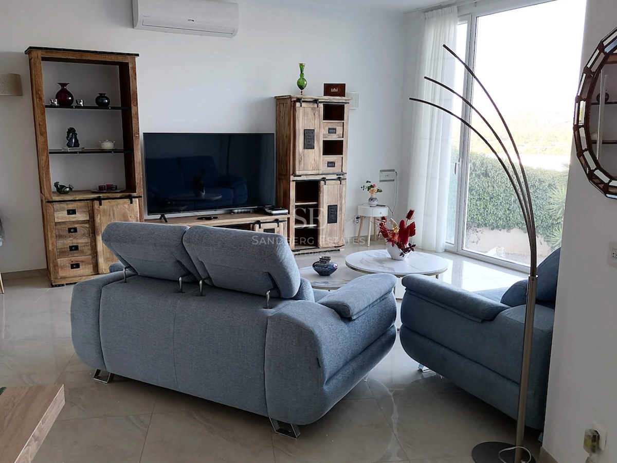 Modern living room featuring blue sofas, rustic wood cabinetry, polished tile flooring, and floor-to-ceiling windows.