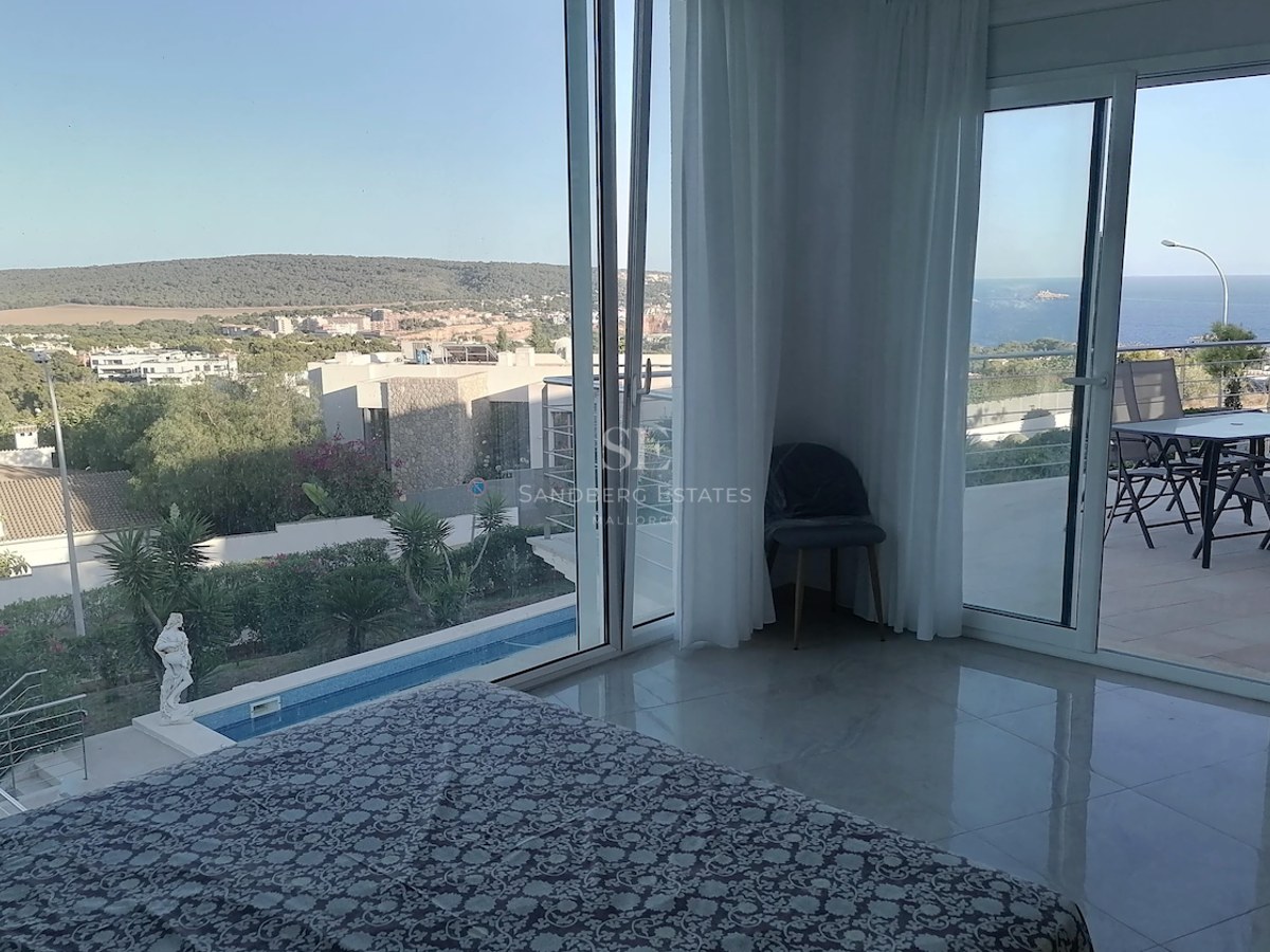 Master bedroom featuring polished marble floors and large glass doors opening to a private terrace overlooking the sea and pool.