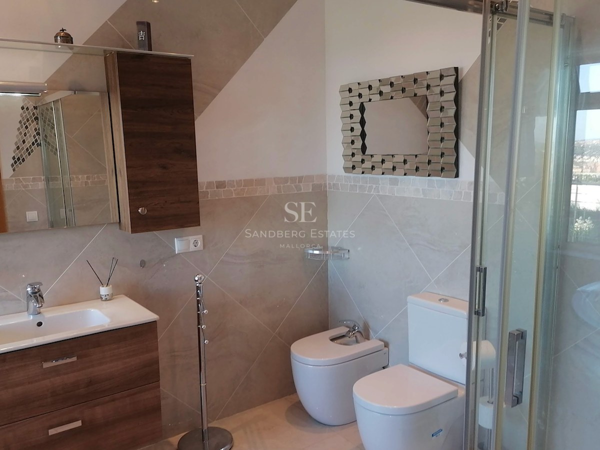 Modern bathroom featuring a wooden vanity, white ceramic toilet and bidet, and a glass-enclosed shower.