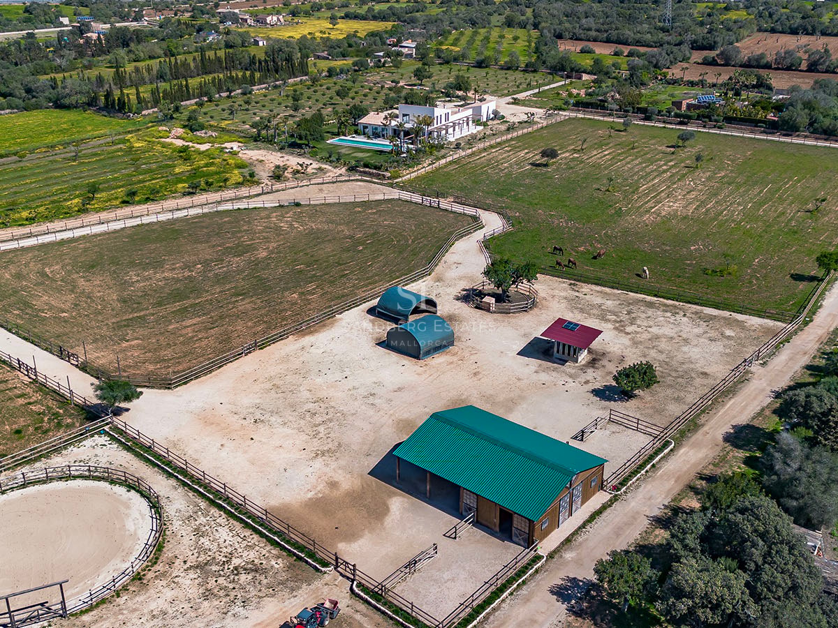 High-angle aerial view of a luxury Mediterranean estate featuring extensive equestrian facilities, stables, and a villa.
