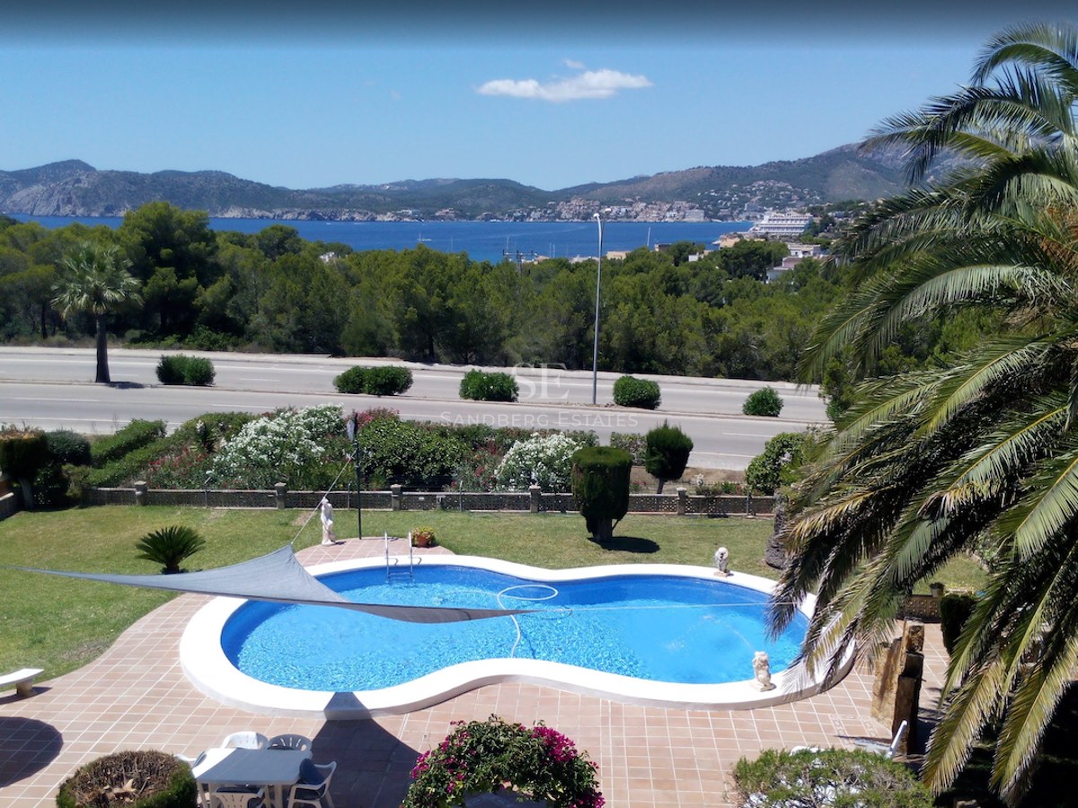 Piscine en forme de haricot entourée de terre cuite et d'un jardin avec vue sur la Méditerranée et les montagnes.