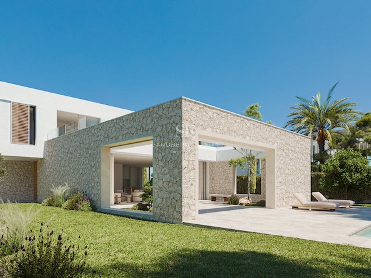 Zeitgenössische Villa von außen mit Natursteinwänden, großen Glasfronten und gepflegtem Rasen unter blauem Himmel.