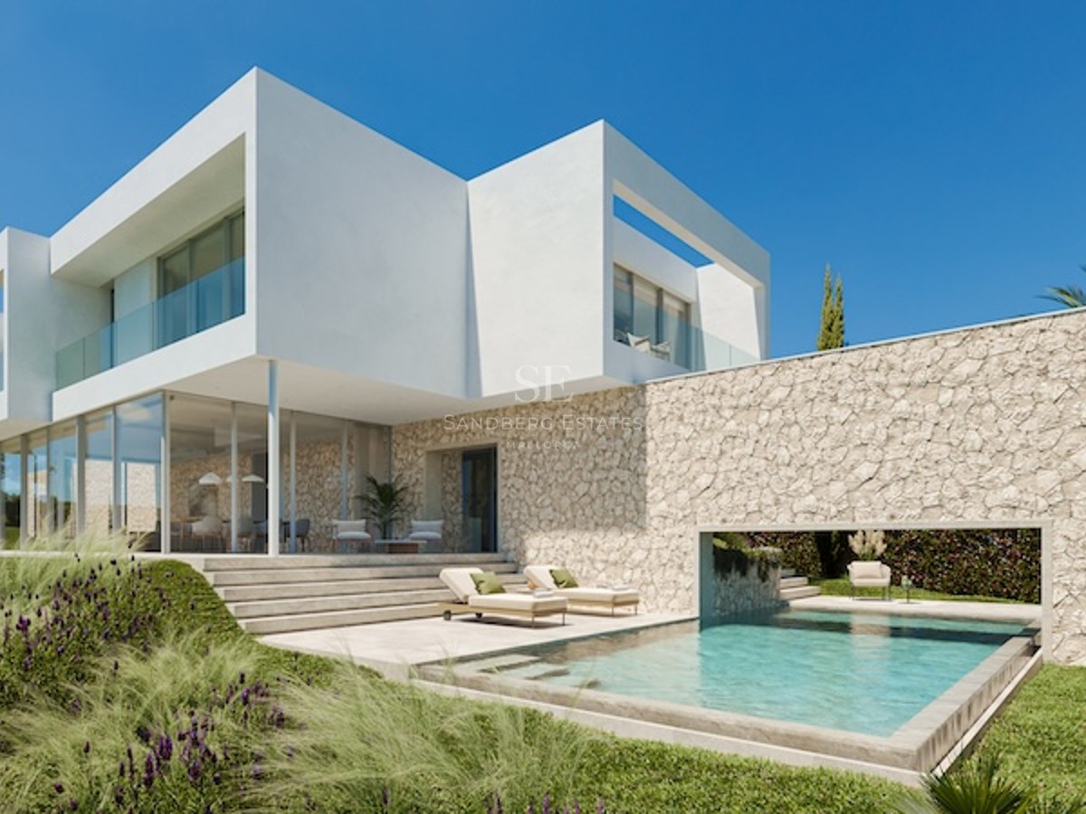 Villa moderne blanche avec murs en pierre, piscine et chaises longues sous un ciel bleu.