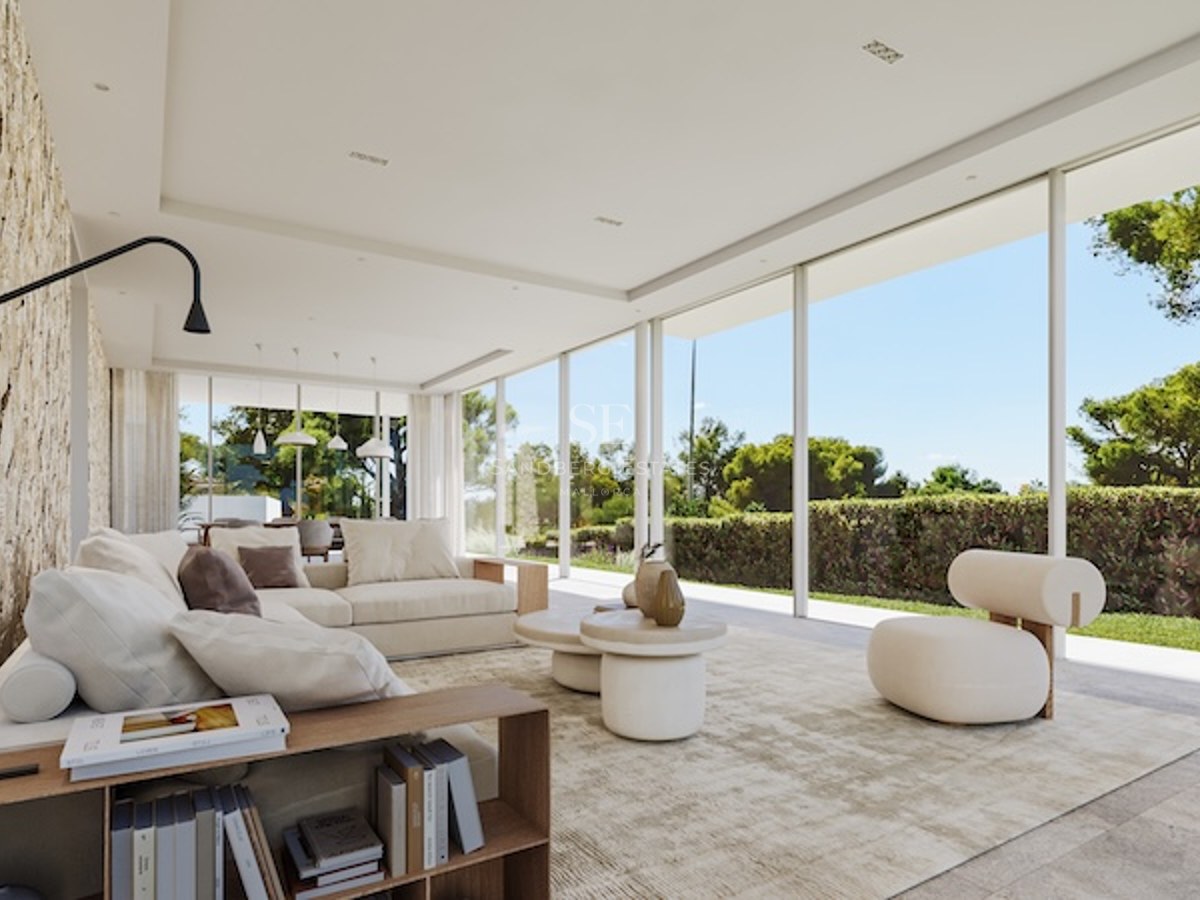 Salon minimaliste spacieux avec baies vitrées toute hauteur, canapé modulable crème et vue sur le jardin.