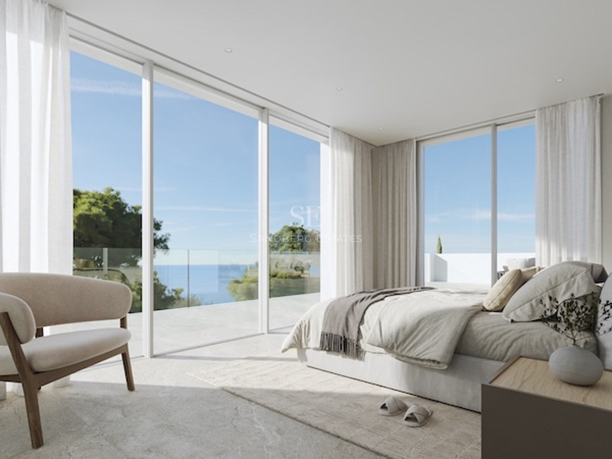 Ett minimalistiskt master bedroom med glasdörrar från golv till tak som leder ut till en stenterrass med utsikt över havet.