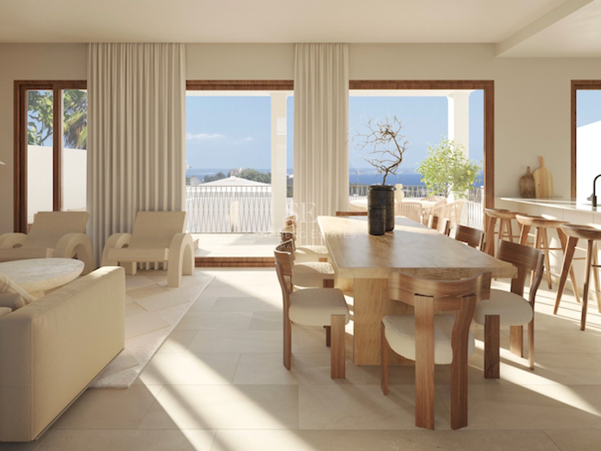 Salle à manger contemporaine avec table en bois massif et vue sur l'océan depuis la terrasse adjacente.