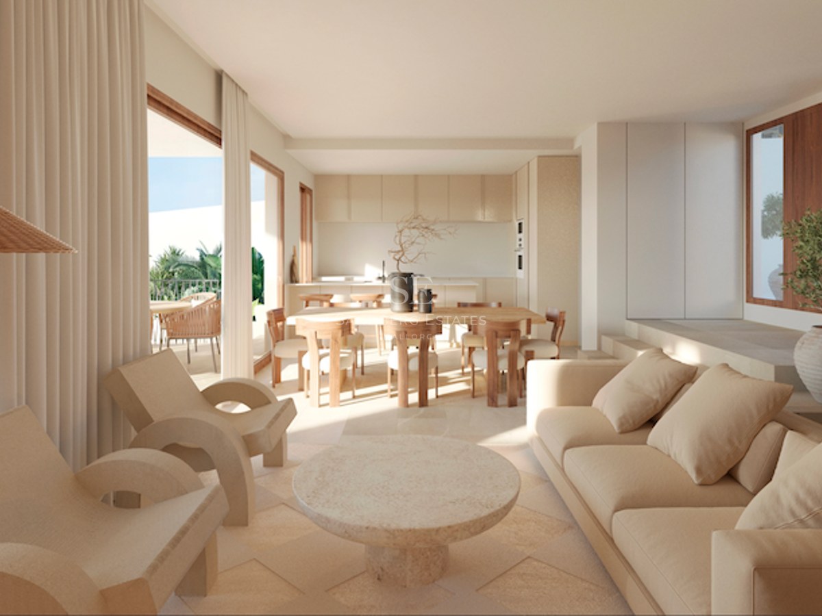 Salon lumineux avec canapés beige, table en pierre et salle à manger en bois menant à une terrasse ensoleillée.