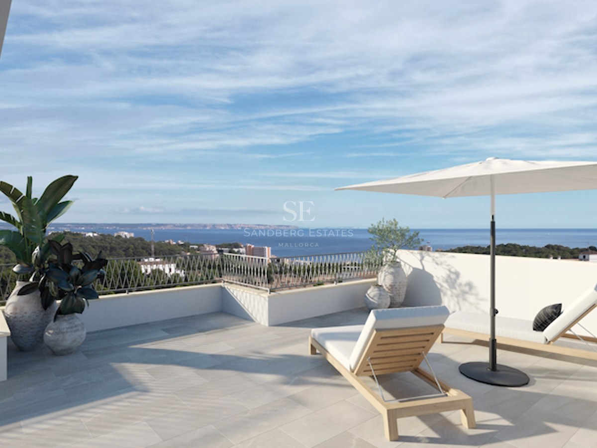 Terrasse ensoleillée avec chaise longue en bois, parasol blanc et vue sur la côte méditerranéenne et la mer bleue.
