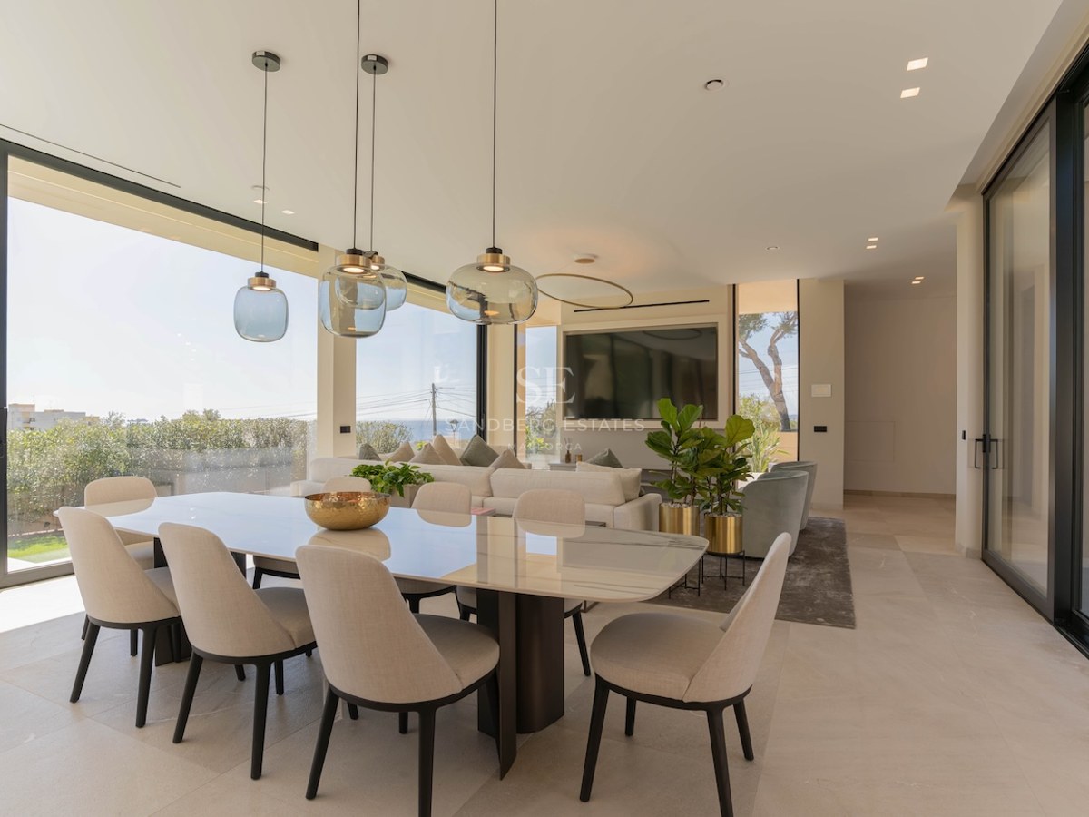 Salle à manger moderne avec table en marbre et baies vitrées offrant une vue imprenable sur la mer.