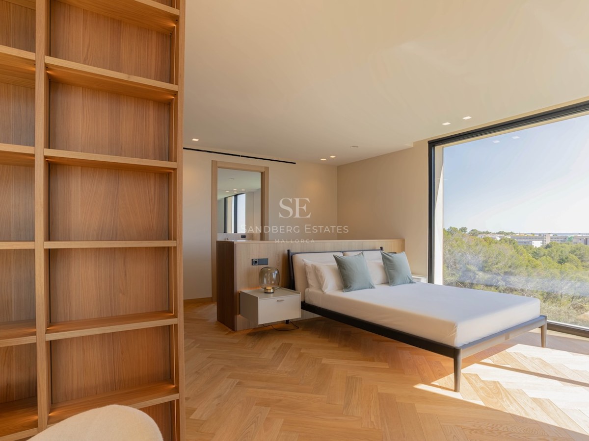 Chambre contemporaine avec parquet en chêne, bibliothèque intégrée et grande baie vitrée donnant sur la nature.
