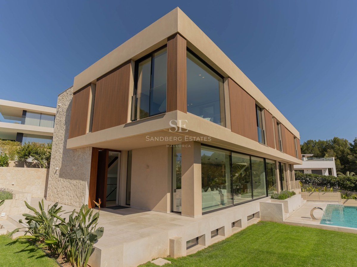 Vue extérieure d'une villa contemporaine de deux étages avec murs en pierre, baies vitrées et piscine.