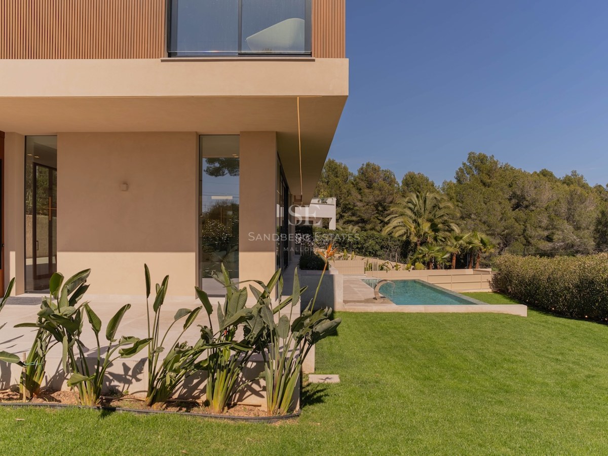 Profil latéral d'une villa moderne à deux étages avec murs couleur sable, accents en bois, pelouse et piscine.