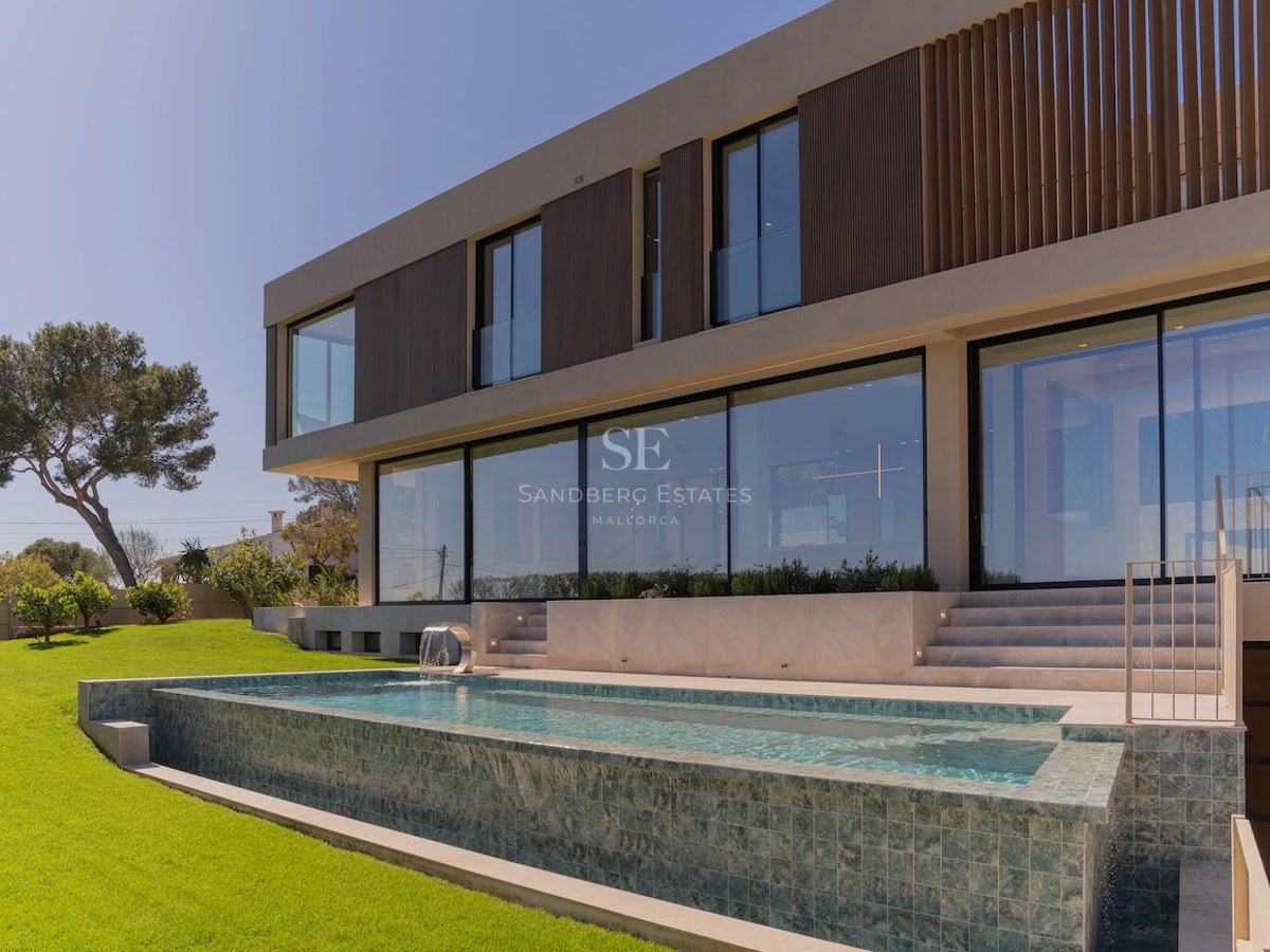 Façade de villa contemporaine sur deux niveaux avec baies vitrées donnant sur une piscine en mosaïque et un jardin.