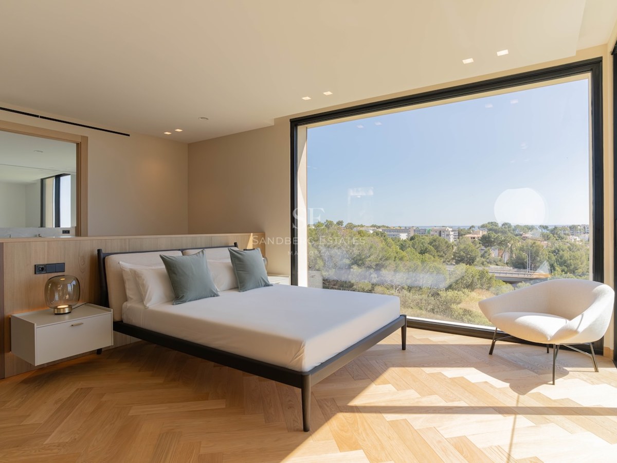 Chambre contemporaine avec parquet en chêne en point de Hongrie et grande baie vitrée donnant sur un paysage verdoyant.