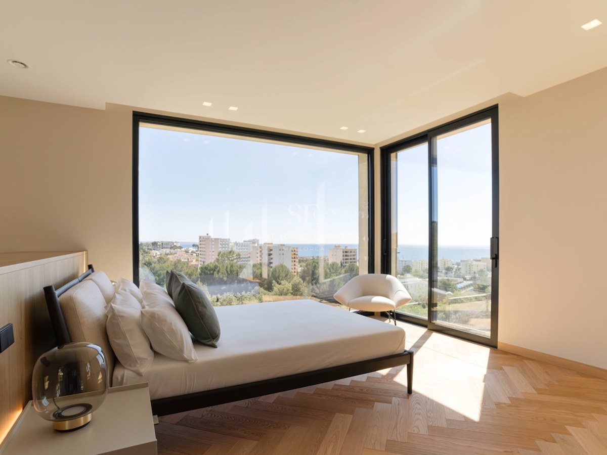 Chambre principale lumineuse avec fenêtres d'angle du sol au plafond, vue sur la mer et parquet en chevrons.
