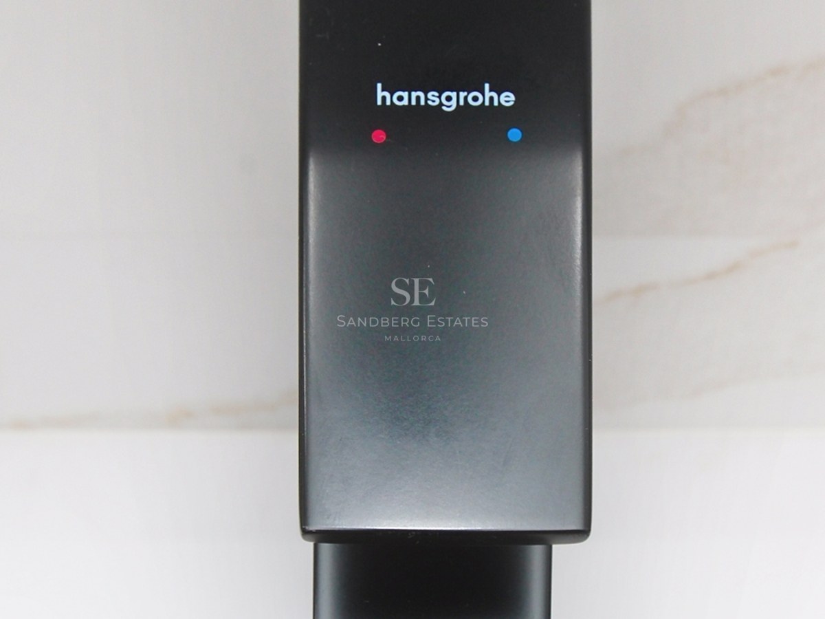Primer plano de un grifo Hansgrohe en acabado negro mate sobre fondo de mármol blanco.