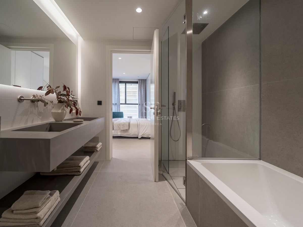 Salle de bain contemporaine avec double vasque grise, douche vitrée, baignoire et vue sur la chambre.