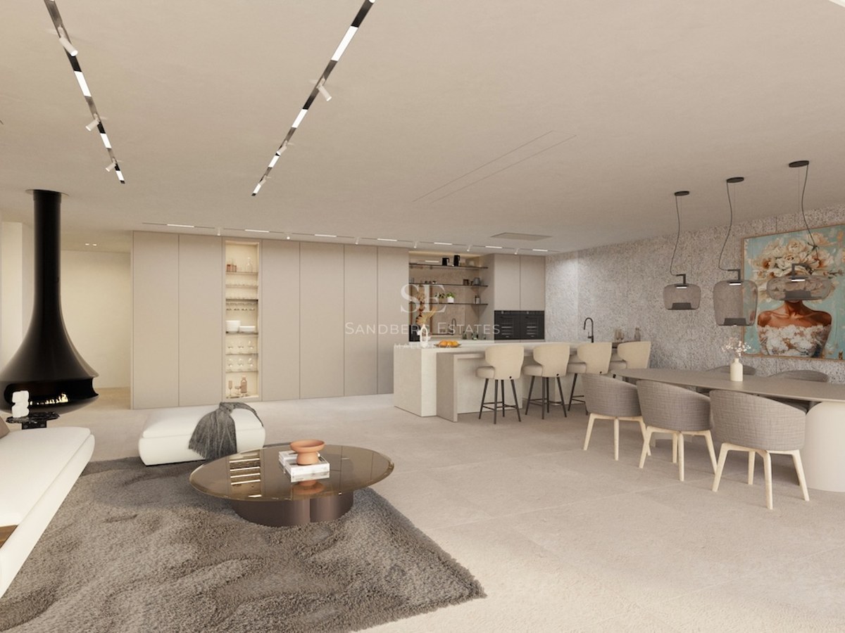 Espace de vie ouvert spacieux avec canapé blanc, cheminée noire design, salle à manger et cuisine aux tons neutres.