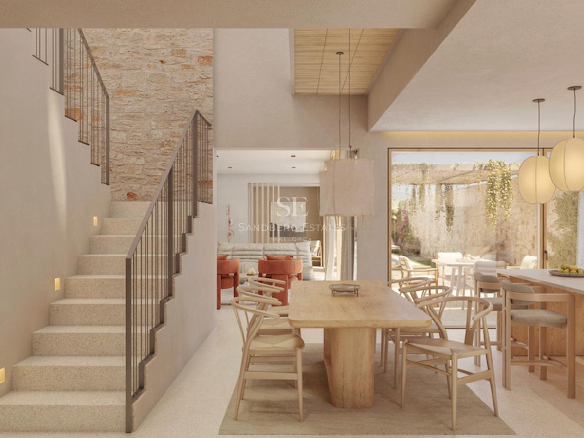 Intérieur moderne lumineux avec une grande table en bois, un mur en pierre et un élégant escalier en pierre.