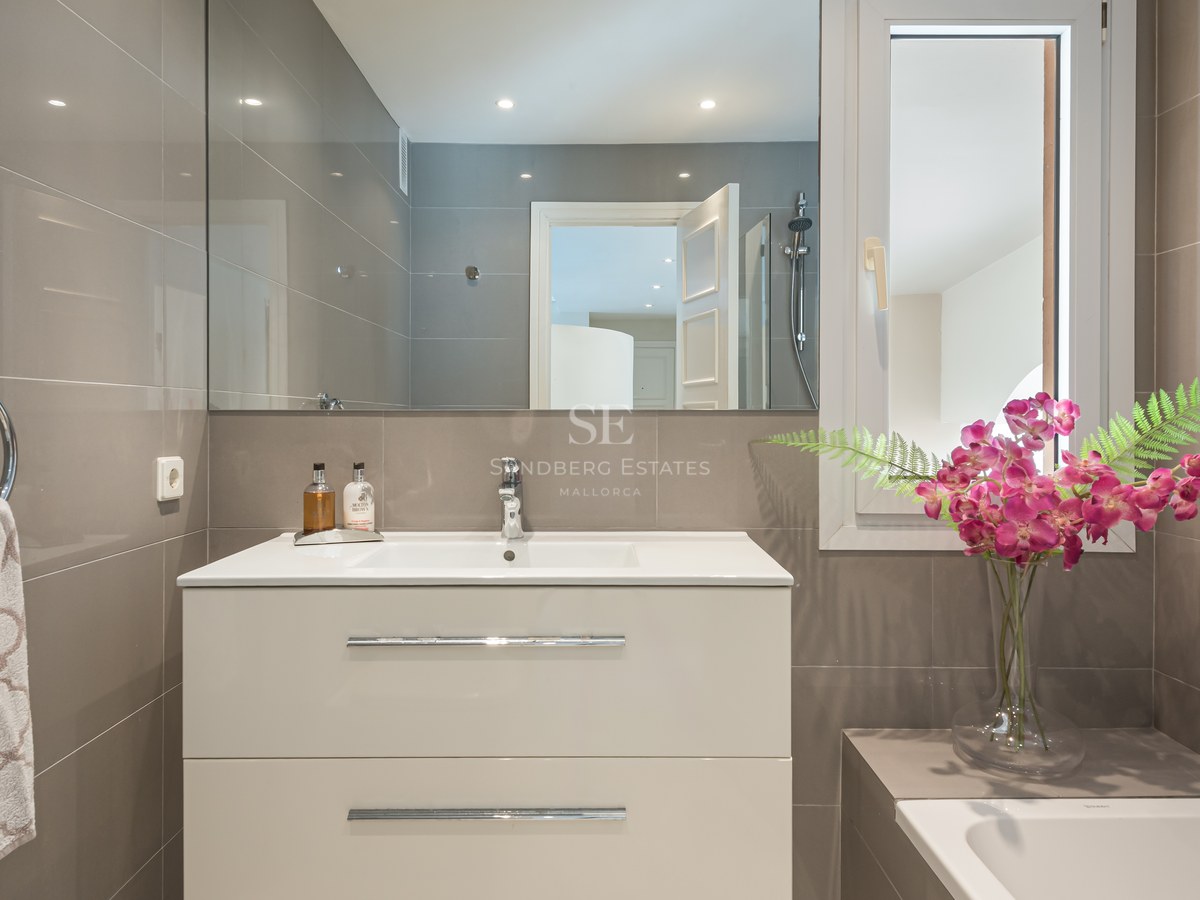 Salle de bains contemporaine avec meuble vasque blanc, grand miroir et carrelage taupe avec accents chromés.