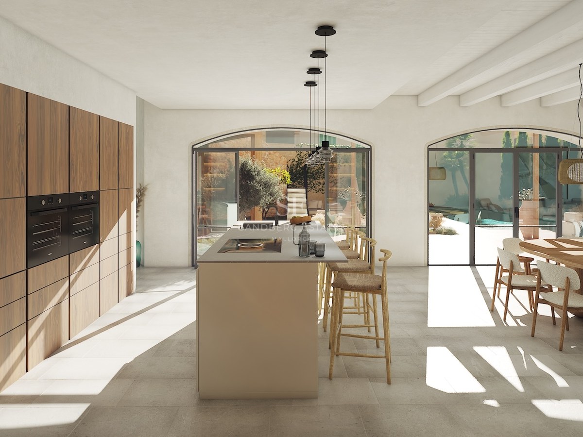 Cuisine moderne à aire ouverte avec îlot central, menuiserie en noyer et portes vitrées cintrées donnant sur un patio.