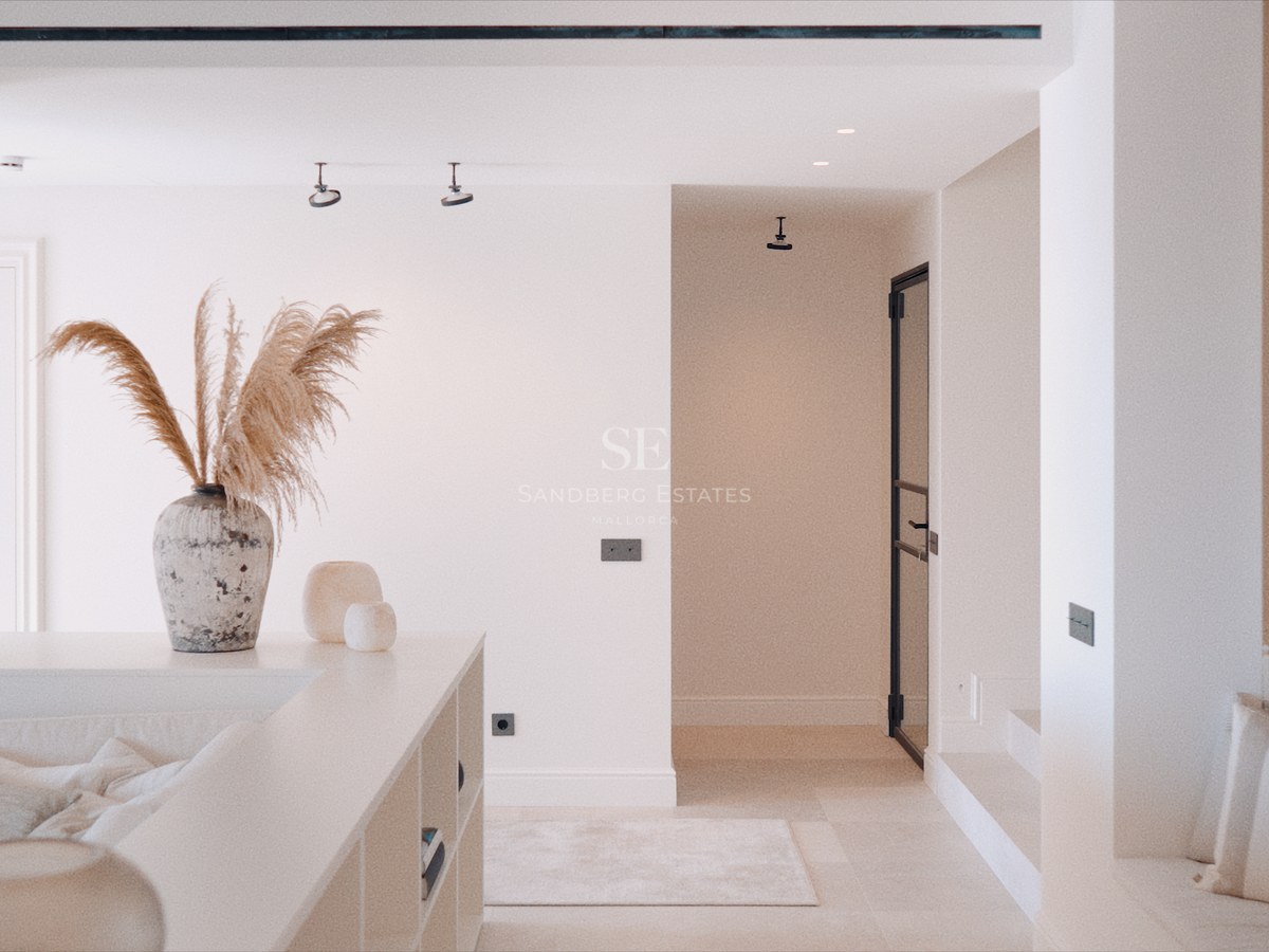 Sunken living area with off-white sofa, decorative pampas grass in a stone vase, and clean white walls.