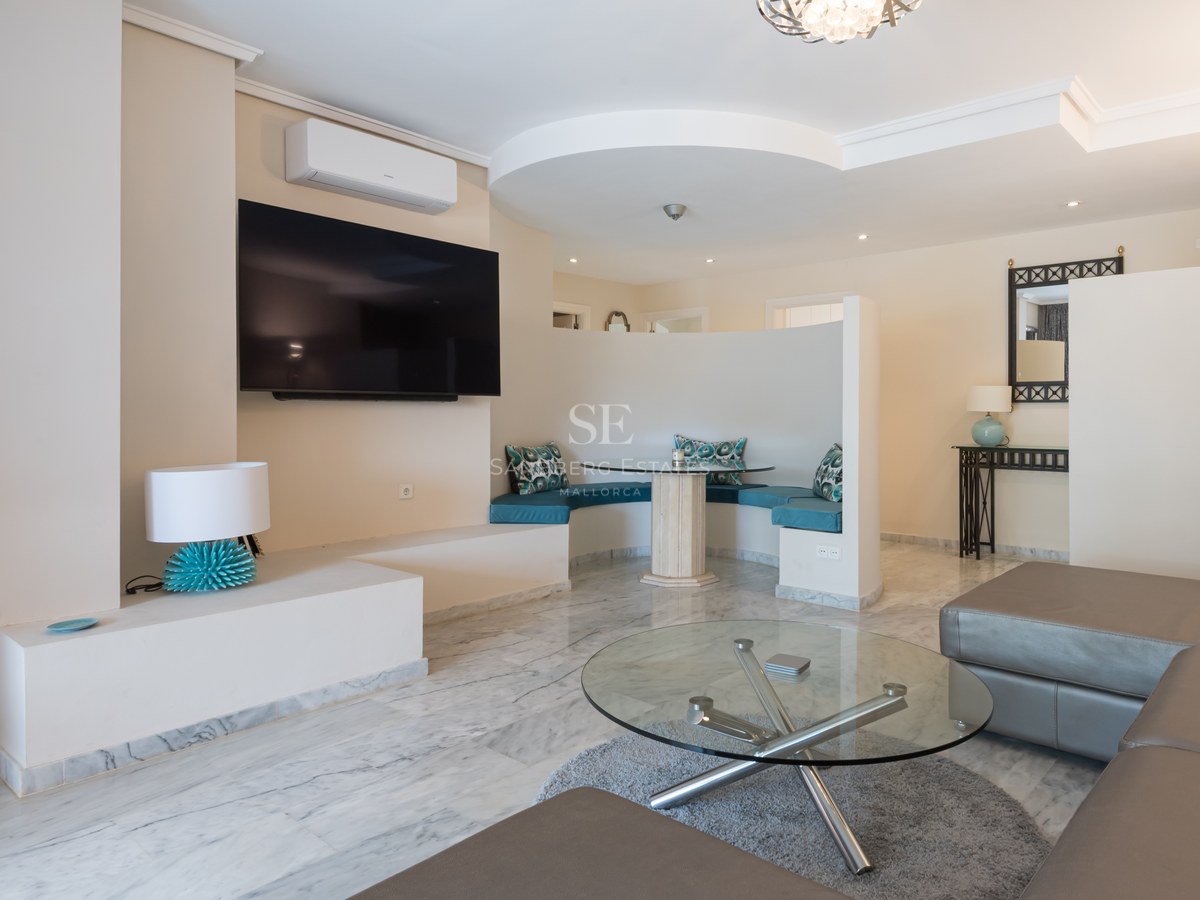 Salon moderne avec sol en marbre, canapé en cuir et un coin petit-déjeuner incurvé avec coussins turquoise.