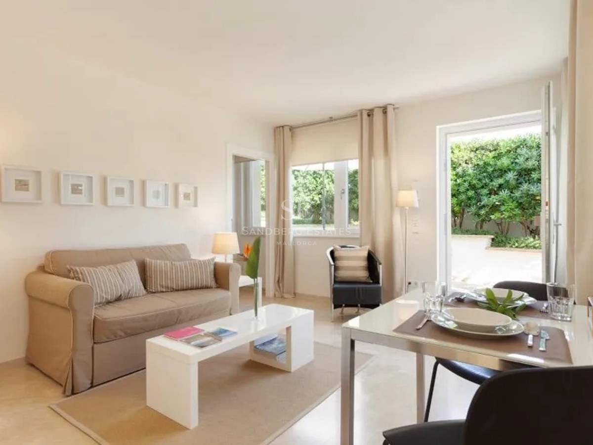 Contemporary cream-toned living room with dining area opening onto a lush private garden via glass doors.